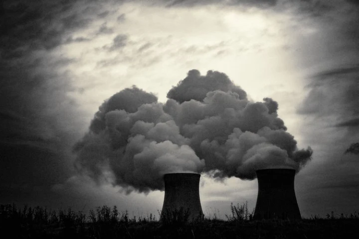 Cooling towers beneath dramatic clouds in black and white